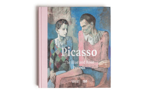 Ein quadratisches Buch mit dem Titel Picasso The Blue and Rose Periods, von oben auf einem weißen Hintergrund fotografiert. Das Cover zeigt ein Gemälde von zwei nachdenklichen jungen Männern in Kostümen vor einem blauen Hintergrund. Der Buchrücken ist aus rosafarbenem Leinen.