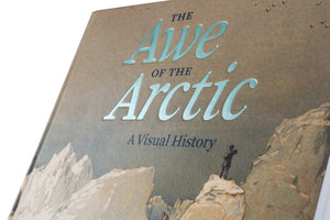 Nahaufnahme des Buchcovers von The Awe of the Arctic, A Visual History. Die Wörter Awe und Arctic sind in einer glänzenden, hellblauen Folienschrift auf einen strukturierten, braunen Karton gedruckt. Das Cover zeigt einen Mann auf einem Felsen, der eine Berglandschaft überblickt.