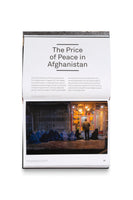 Eine aufgeschlagene Seite eines Buches mit dem Titel The Price of Peace in Afghanistan. Darunter befindet sich ein Foto, das nachts Frauen und Kinder in blauen Burkas zeigt, die auf dem Bürgersteig vor einer hell erleuchteten Bäckerei in Kabul, Afghanistan, sitzen und um Brot betteln. Ein Mann steht vor dem Geschäft. Die Seite enthält auch Text über die Wirtschaftskrise des Landes.