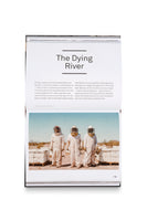 Ein aufgeschlagenes Magazin auf Seite 119 mit dem Titel The Dying River. Ein großes Foto zeigt drei Imker in weißen Schutzanzügen in der Wüste Arizonas. Sie stehen vor Bienenstöcken, während ein Schwarm Bienen um sie herumfliegt.