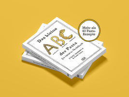 Ein Stapel des Buches Das kleine ABC der Pasta liegt auf einem gelben Hintergrund. Das Cover zeigt die Buchstaben A, B und C, die aus verschiedenen Nudelsorten geformt sind. Ein gelber Aufkleber hebt hervor, dass das Buch mehr als 40 Pasta-Rezepte enthält.