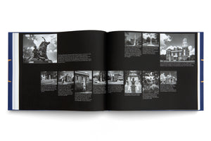 Ein aufgeschlagenes Buch mit blauem Einband, das auf einer weißen Fläche liegt. Die schwarzen Seiten zeigen verschiedene Schwarz-Weiß-Fotografien von Denkmälern der Konföderierten in Georgia, USA, zusammen mit erklärendem englischem Text.