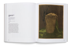 Ein aufgeschlagenes Buch zeigt auf der linken Seite einen Beschreibungstext und auf der rechten Seite das Kunstwerk Weiblicher Rückenakt auf grünem Tuch. Das Werk zeigt den beleuchteten Rücken einer sitzenden nackten Frau auf einem leuchtend grünen Tuch vor einem dunklen Hintergrund.