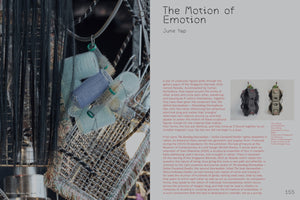 Eine Seite aus einer Kunstpublikation mit dem Titel The Motion of Emotion. Links ist eine Nahaufnahme einer komplexen Skulptur aus Haarlockenwicklern, Bürsten und schwarzen Haaren. Rechts befindet sich auf grauem Grund ein Artikel und ein kleines Bild von zwei weiteren totemartigen Skulpturen.