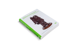 Ein weißes Buch mit dem Titel Lexikon der Lebensmittel als Kunstmaterial. Auf dem Cover steckt ein schokoladenbrauner Buttplug in der Form eines Gartenzwergs durch einen Ausschnitt im Buchdeckel. Der Buchrücken ist grün.