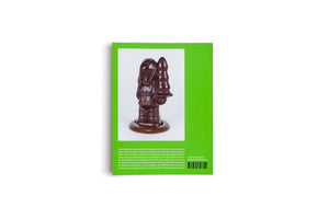 Die Rückseite eines Buches mit einem leuchtend grünen Einband. Auf dem Einband ist eine Fotografie einer glänzenden Schokoladenfigur zu sehen, die eine Person in dicker Winterkleidung darstellt, die einen tannenbaumartigen Gegenstand hält. Unter dem Bild befinden sich ein deutscher Textblock, die ISBN und ein Barcode.
