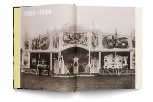 Eine Schwarz-Weiß-Fotografie in einem offenen Buch zeigt ein prächtiges Wanderkino um 1900. Die aufwendig gestaltete Fassade im Jugendstil ist mit großen Gemälden und Ornamenten verziert. Auf der linken Seite des Buches stehen die Jahreszahlen 1895–1909.
