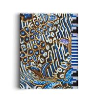 Eine Leinwand, bespannt mit einem Stoff im Batik-Stil. Das komplexe Muster zeigt organische, blumenartige Formen und gewellte Linien in Blau-, Braun- und Weißtönen auf schwarzem Grund, ergänzt durch einen geometrischen, schwarz-weiß gestreiften Rand auf der rechten Seite.