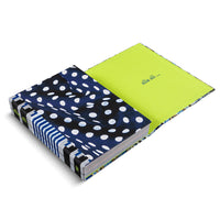 Ein aufgeschlagenes Hardcover-Buch auf weißem Hintergrund. Der Einband ist mit einem dunkelblauen Stoff mit unregelmäßigen weißen Punkten bezogen. Der Buchrücken hat ein blau-weiß gestreiftes Muster. Die neongrüne Innenseite des Deckels zeigt den Schriftzug alia ali ...