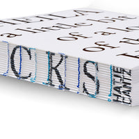 Eine Nahaufnahme des Rückens eines dickes Buches mit offener Fadenheftung. Blaue und türkise Fäden halten die Seiten zusammen und durchkreuzen schwarze Buchstaben, die auf die Kanten der Seiten gedruckt sind.