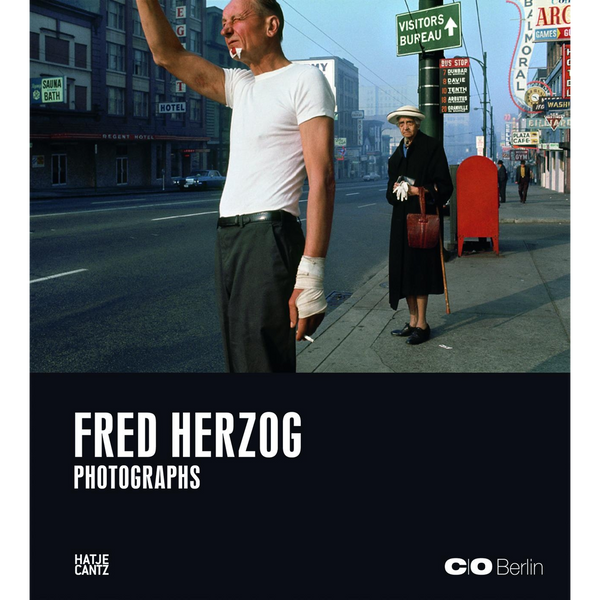 Das Cover des Fotobuchs Fred Herzog Photographs zeigt einen Mann mit bandagierter Hand und eine ältere Person mit Hut an einer belebten Straßenecke in der Stadt.