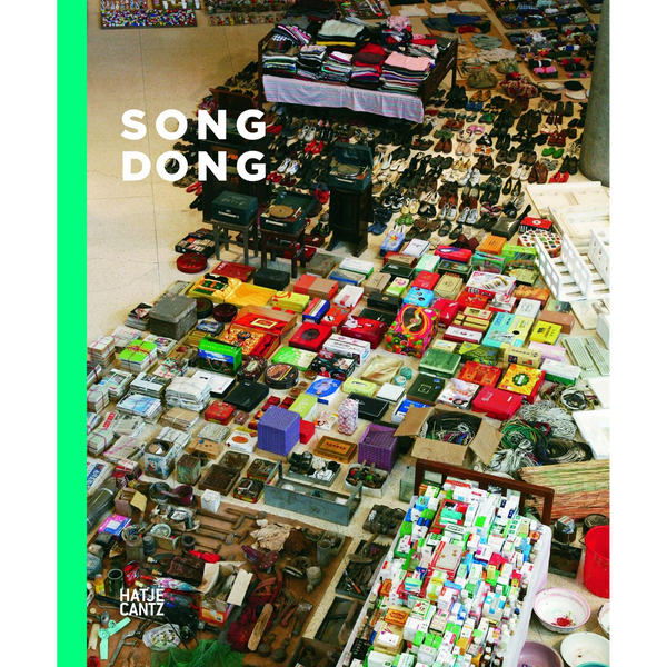 Das Buchcover von Song Dong zeigt eine von oben fotografierte Kunstinstallation, bei der unzählige Haushaltsgegenstände wie Schuhe, Schachteln und Kleidung sorgfältig auf dem Boden angeordnet sind.