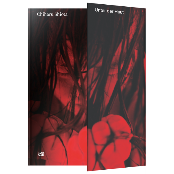 Das Buchcover für Chiharu Shiotas Werk Unter der Haut zeigt ein Gesicht, das von dunklen Fäden oder Haaren verdeckt wird, alles in einer intensiven rot-schwarzen Farbgebung.