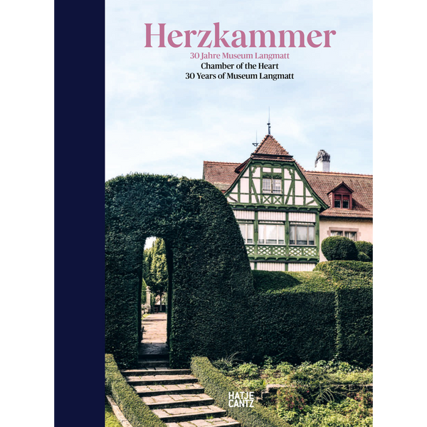Das Buchcover von Herzkammer zeigt eine Steintreppe, die zu einem Torbogen in einer hohen Hecke führt. Dahinter ist das historische Fachwerkhaus des Museums Langmatt zu sehen.
