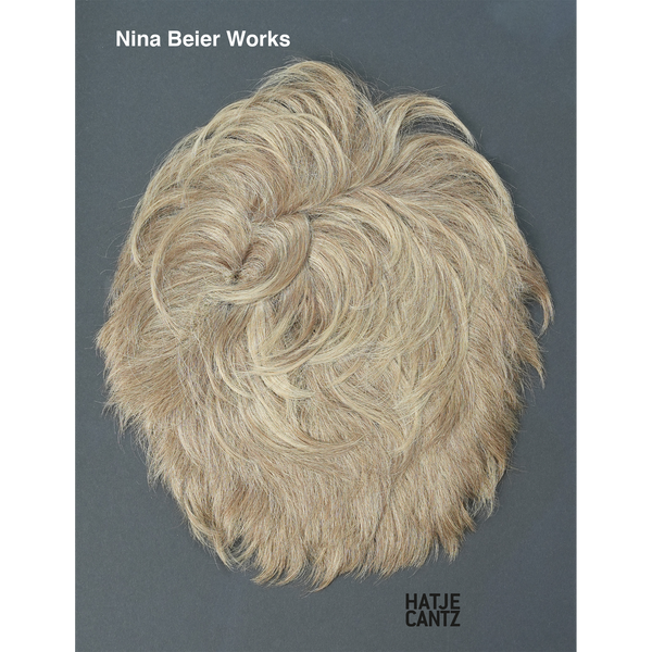 Ein blondes Haarteil liegt in Wirbelform auf dem grauen Cover des Buches Nina Beier Works.