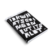 Ein schwarzes Buch von Stefan Marx mit dem Titel Monotypien | Monotypes liegt schräg auf einem weißen Hintergrund. Der Einband zeigt in großer, weißer, handgezeichneter Blockschrift den Satz I D K WHATS GOING ON BUT ITS A LOT.