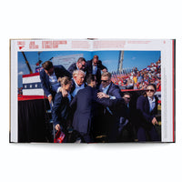 Eine aufgeschlagene Seite in einem Buch, die ein großes Foto des Attentatsversuchs auf Donald Trump zeigt. Trump, mit Blut an seinem rechten Ohr, wird von mehreren Secret-Service-Agenten umringt und von einer Bühne eskortiert. Im Hintergrund ist eine Menschenmenge bei einer Kundgebung im Freien mit vielen amerikanischen Flaggen zu sehen. Die Überschrift über dem Foto lautet Attempted Assassination of Donald Trump.