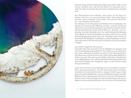 Eine Seite aus einer Publikation mit einem geteilten Layout. Links ist der Ausschnitt eines großen, runden Kunstwerks zu sehen, dessen obere Hälfte einen glatten Farbverlauf in Violett, Rot und Grün aufweist, während die untere Hälfte eine dicke, weiße und rissige Textur hat, die teilweise abgebröckelt ist. Rechts neben dem Bild steht schwarzer deutscher Text in mehreren Absätzen auf weißem Grund.