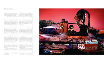 Eine Doppelseite aus einem Buch, auf der rechts die Künstlerin Julie Mehretu mit Sonnenbrille in der offenen Fahrerkabine eines Rennwagens sitzt. Das Auto ist ein BMW Art Car, das mit einem bunten, abstrakten Muster und Sponsorenlogos vor einem pinken Hintergrund gestaltet ist.