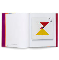 Ein aufgeschlagenes Kunstbuch, das auf der rechten Seite ein abstraktes Gemälde zeigt, das aus einem roten, nach unten gerichteten Dreieck und einem gelben, nach oben gerichteten Dreieck besteht, die eine Sanduhrform bilden.