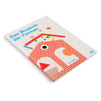 Ein schräg auf einer weißen Oberfläche liegendes Buch mit dem Titel Das Museum der Formen. Das Cover zeigt eine bunte, grafische Illustration eines Hauses aus einem roten Backsteinmuster und anderen geometrischen Formen.