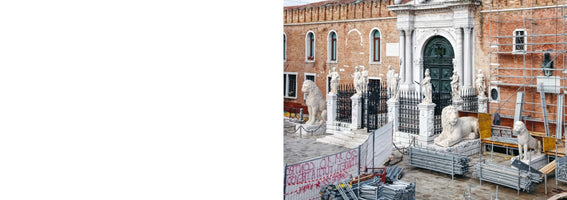 Der Eingang des Arsenals von Venedig mit seinen Marmorstatuen und Löwen, umgeben von einem Baugerüst und Baumaterialien während einer Renovierung.